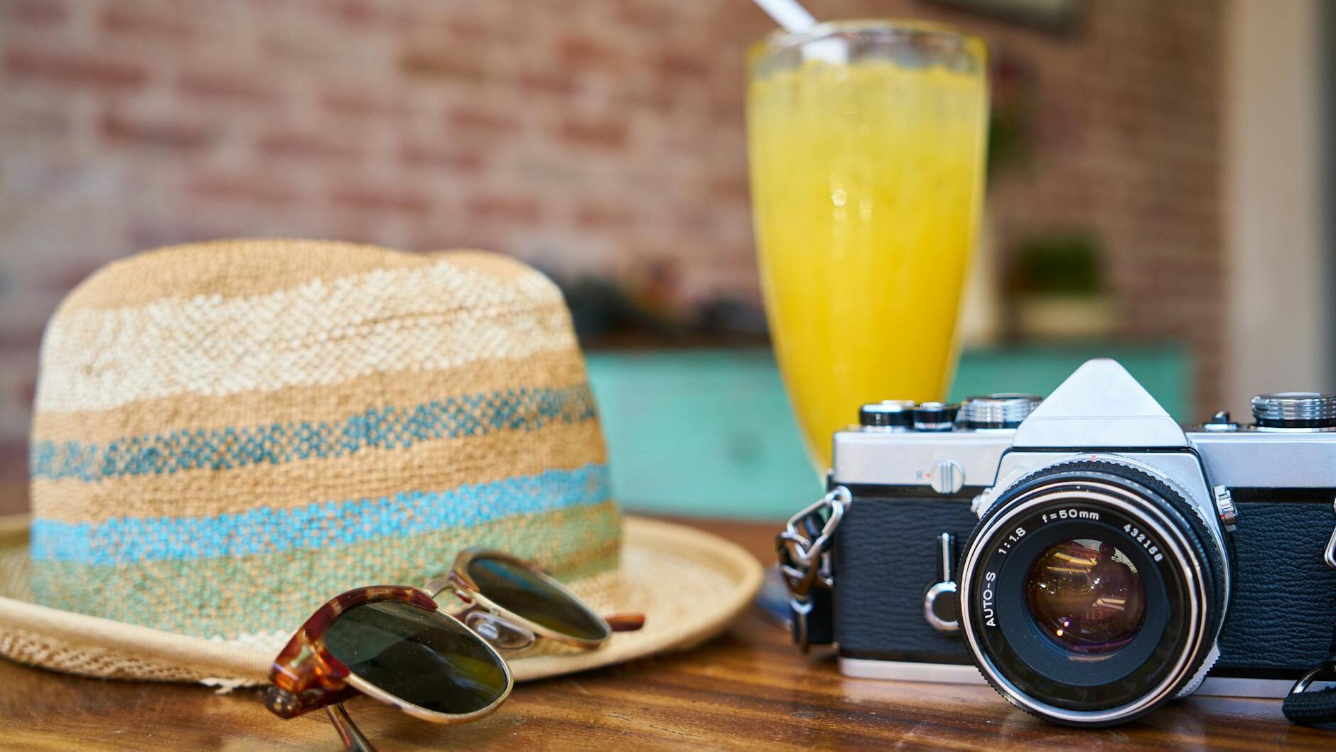 gray and black dslr camera beside sun hat and sunglasses