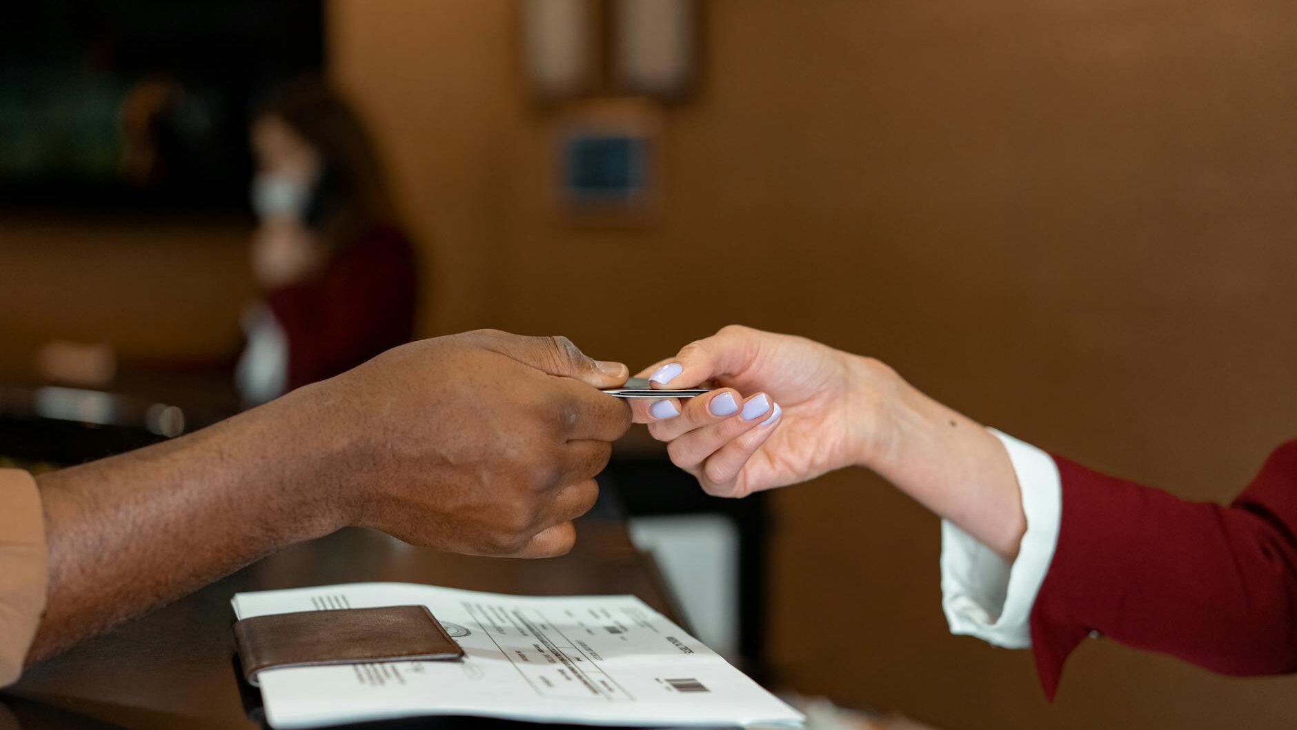 man handing a credit card to a hotel receptionist